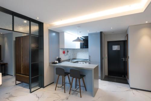a kitchen with a counter and two stools at Gloucester Hotel Cheongju in Cheongju