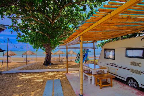 an rv parked next to a beach with a tree at Beach House Camp in Na Jomtien
