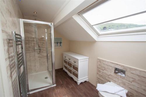 a bathroom with a shower and a toilet and a skylight at Acorn Cottage in Ambleside