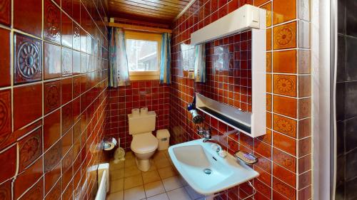 a red tiled bathroom with a sink and a toilet at Ferienhaus Rehbock RB0 in Blatten bei Naters