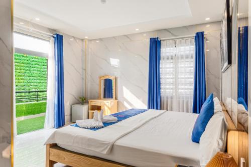 Schlafzimmer mit einem großen Bett und blauen Vorhängen in der Unterkunft KISS Hotel Tân Bình in Ho-Chi-Minh-Stadt