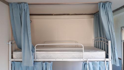 a bunk bed in a bedroom with blue curtains at ゲストハウスのスタジオ５１ in Sasebo