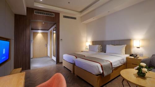 Habitación de hotel con cama y TV en Orana Aurnum en Nueva Delhi