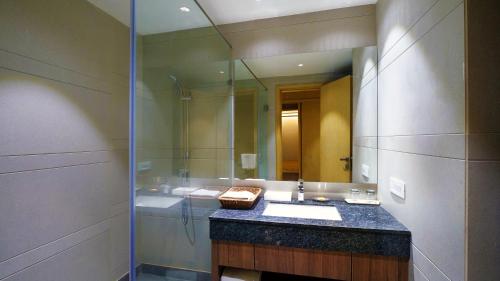 Orana Aurnum في نيودلهي: حمام مع حوض ومرآة كبيرة