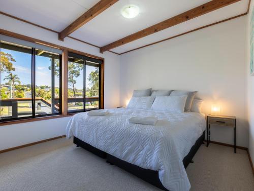 um quarto com uma cama grande e janelas em Surf Beach Escape em Surf Beach