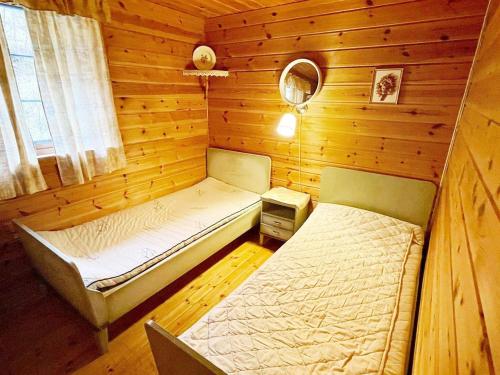 a bedroom with two beds in a wooden cabin at Three-Bedroom Holiday home in Åkra in Kyrping