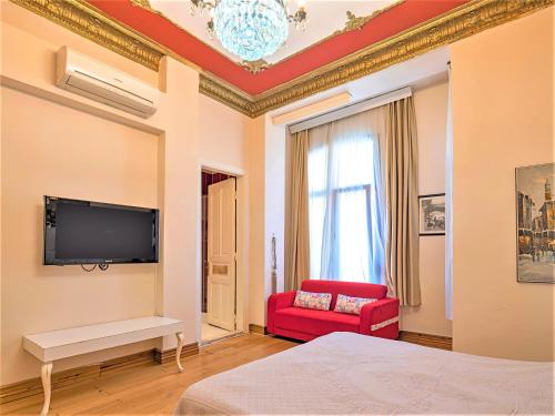 a bedroom with a tv on the wall and a red chair at Ragip Pasha Apartments in Istanbul