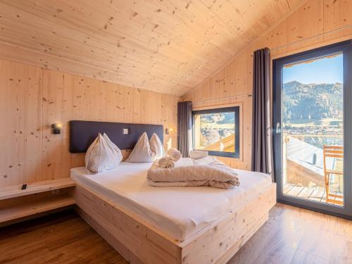 a bed in a wooden room with a large window at Cozy Chalet in Steinach am Brenner with Balcony and sauna in Steinach am Brenner