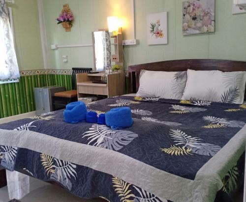 a bedroom with a large bed with blue stuffed animals on it at ริมน้ำ บ้านพรศรี โฮมสเตย์ in Ban San Ton Thong