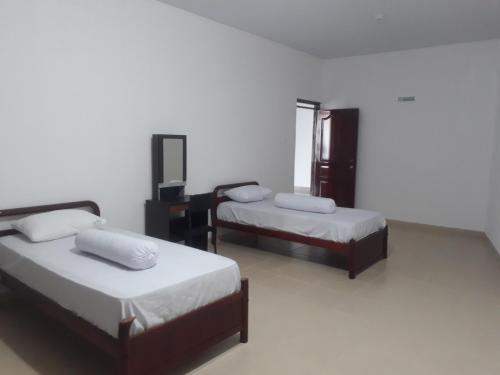 two beds in a room with white walls at HAPDESKO HOMESTAY in Batam Center
