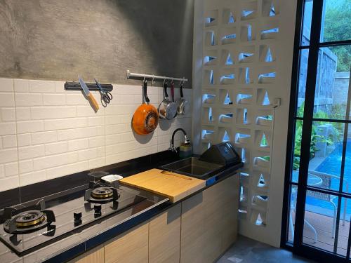 uma cozinha com um fogão, um lavatório e uma janela em Villa Penny II em Batu