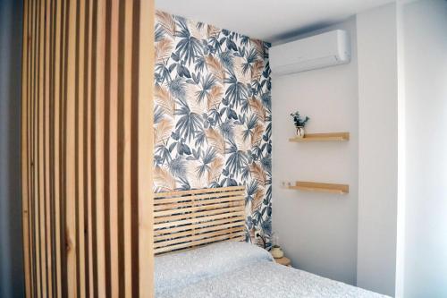 1 dormitorio con 1 cama y papel pintado con motivos florales en Apto Málaga centro histórico Parking Priv Gratuito en Málaga