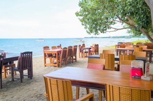a restaurant on the beach with tables and chairs at RedDoorz at Tanjung Alam Hotel Lovina in Buleleng