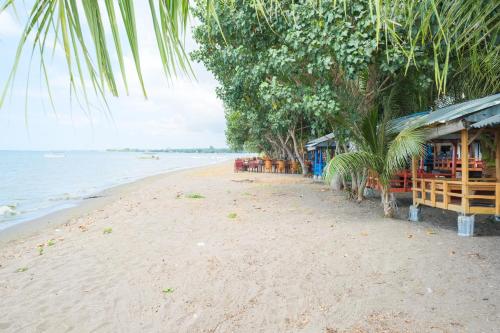 a beach with tables and chairs on the shore at RedDoorz at Tanjung Alam Hotel Lovina in Buleleng