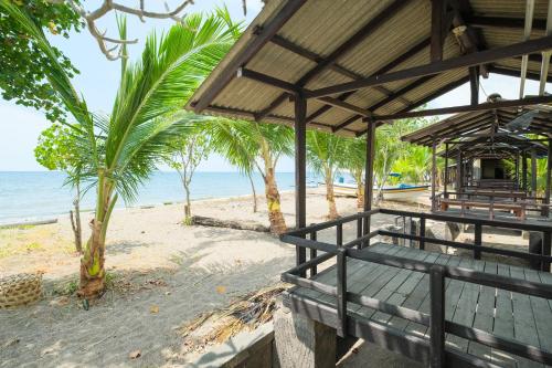 a pavilion on the beach with palm trees and the ocean at RedDoorz at Tanjung Alam Hotel Lovina in Buleleng