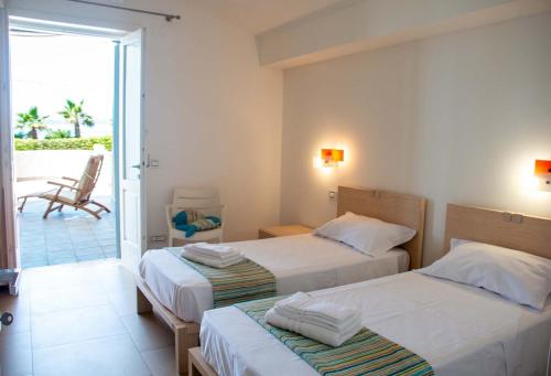 ein Hotelzimmer mit 2 Betten und einem Balkon in der Unterkunft Villa White Dahlia in Torre Suda