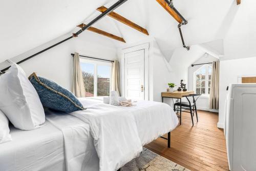 a white bedroom with a large bed and a desk at Stately Studio Apartment in Detroit