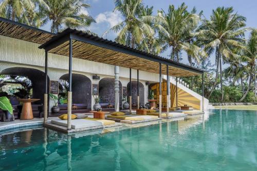 a pool at a resort with palm trees in the background at Soulshine Bali in Ubud