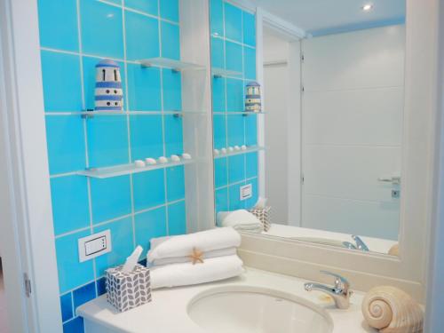 ein blau gefliestes Bad mit einem Waschbecken und einem Spiegel in der Unterkunft Villa White Dahlia in Torre Suda