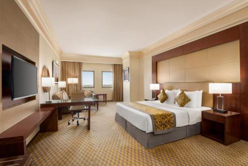 a large hotel room with a bed and a desk at Wyndham Garden Dammam in Dammam