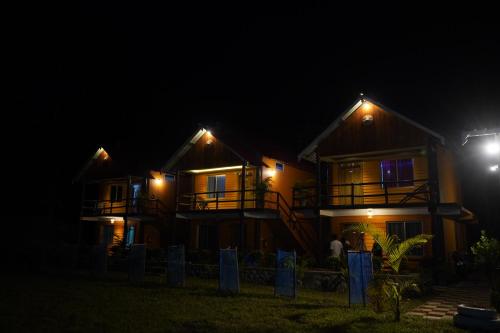 a couple of houses at night with lights at The PugMark Wildlife Resort in Jyoti Gaon