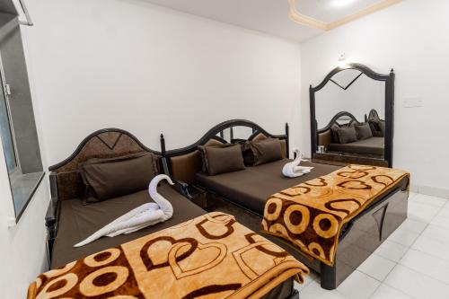 Cette chambre comprend 2 lits et un miroir. dans l'établissement Hotel Vyankatesh & Pure Veg Restaurant, à Mahabaleshwar