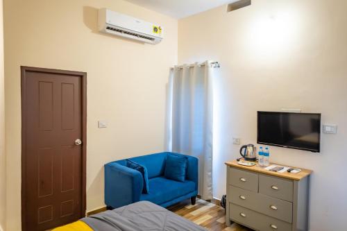 um quarto com uma cadeira azul e uma televisão em Coastal Pearl Home Stay, Murudeshwar em Māvalli