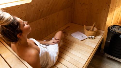 a woman is sitting in a sauna at Hof van Salland Hellendoorn in Hellendoorn