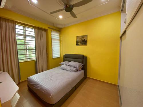 een slaapkamer met gele muren en een bed met 2 kussens bij Homestay LA Kota Bharu in Kota Bharu