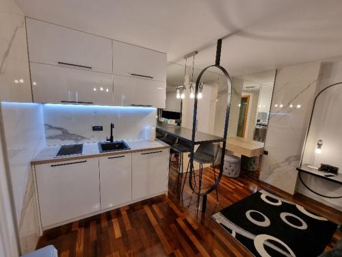 a kitchen with white cabinets and a sink and a table at Apartman Vučko 118 in Jahorina