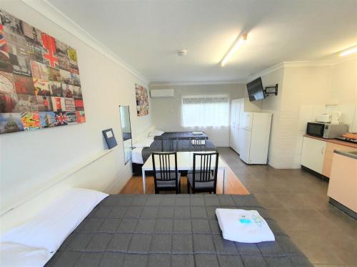 a room with a bed and a table and a kitchen at Maria Motel in Moree