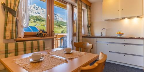 a kitchen with a table and a view of a mountain at Garnì Lasteis B&B - apartments in La Villa