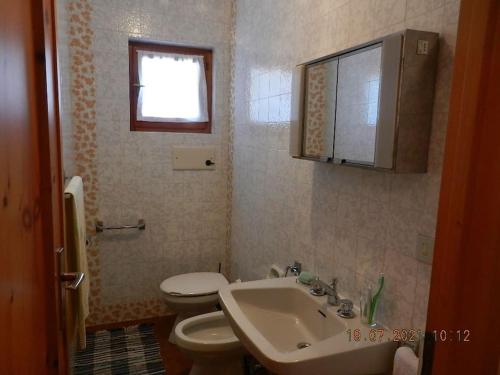 een badkamer met een wastafel, een toilet en een raam bij Appartamento con splendida vista su pista Stelvio in Bormio