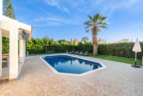 a swimming pool in a backyard with a palm tree at Bungalow Casa Bella by Ezoria Villas in Coral Bay