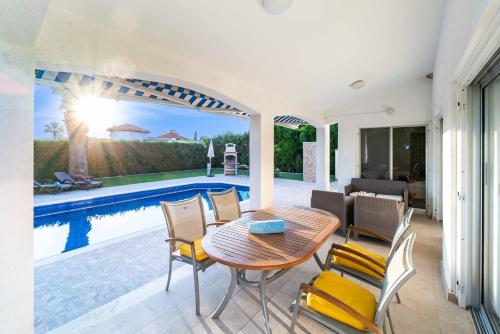 a patio with a table and chairs next to a pool at Bungalow Casa Bella by Ezoria Villas in Coral Bay