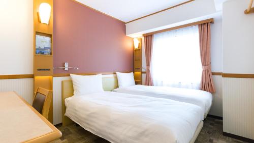 Postel nebo postele na pokoji v ubytování Toyoko Inn JR Yokohama sen Sagamihara Ekimae