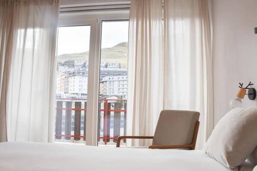 a bedroom with a bed and a chair and a window at Envalira Vacances - Menta in Pas de la Casa