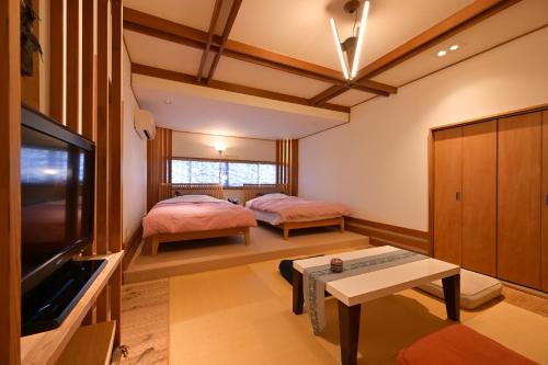 a living room with two beds and a tv at Akari no Yado Okabe in Shibukawa