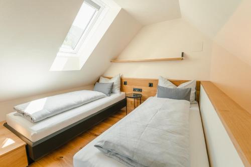 a attic bedroom with two beds and a window at Ferienhaus Holzer in Weissensee