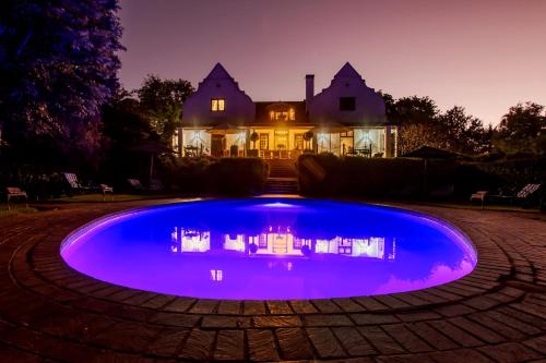 a large blue swimming pool in front of a house at Vredenburg Manor House in Somerset West