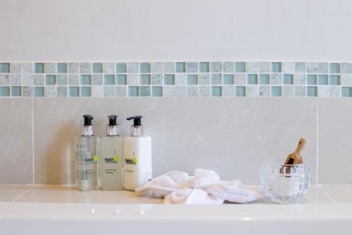 a bathroom counter with two bottles of soap and towels at Vredenburg Manor House in Somerset West