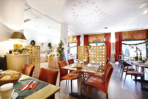 Ambiente Langenhagen Hannover by Tulip Inn في هانوفر: غرفة طعام مع طاولات وكراسي في مطعم