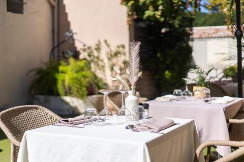 two tables with white table cloths and wine glasses at Logis Hôtel La Fenière in La Bouilladisse