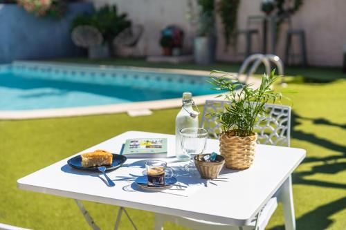 a white table with a plate of food and a drink at Logis Hôtel La Fenière in La Bouilladisse