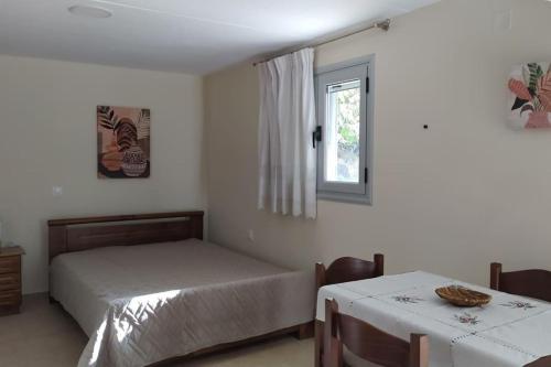 1 dormitorio con 2 camas, ventana y mesa en Tzoumerka Guest House, en Rámia