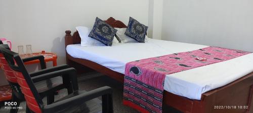 a bedroom with two beds and a chair at Hotel Neel Dipayan in Bāghmundi