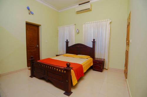 a bedroom with a bed with an orange comforter at KRISHNAGIRI homes in Guruvāyūr