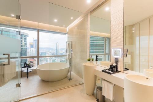 baño con bañera, 2 lavabos y ventana en Banyan Signatures Pavilion Kuala Lumpur by Opus Hospitality, en Kuala Lumpur