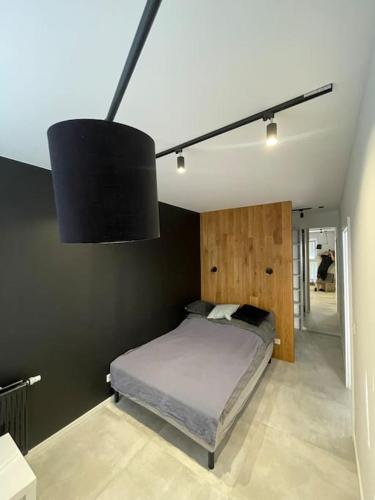 a bedroom with a bed and a black wall at Piękny i nowy apartament, z darmowym parkingiem in Łódź