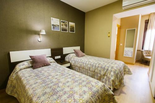 two beds in a hotel room with two beds sidx sidx sidx at Hospedería Castilla Plaza Mayor in Ciudad-Rodrigo